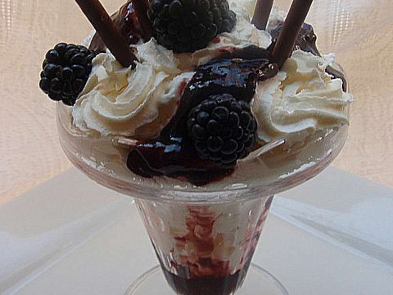 Copa de helado de yogur con salsa de moras y nata