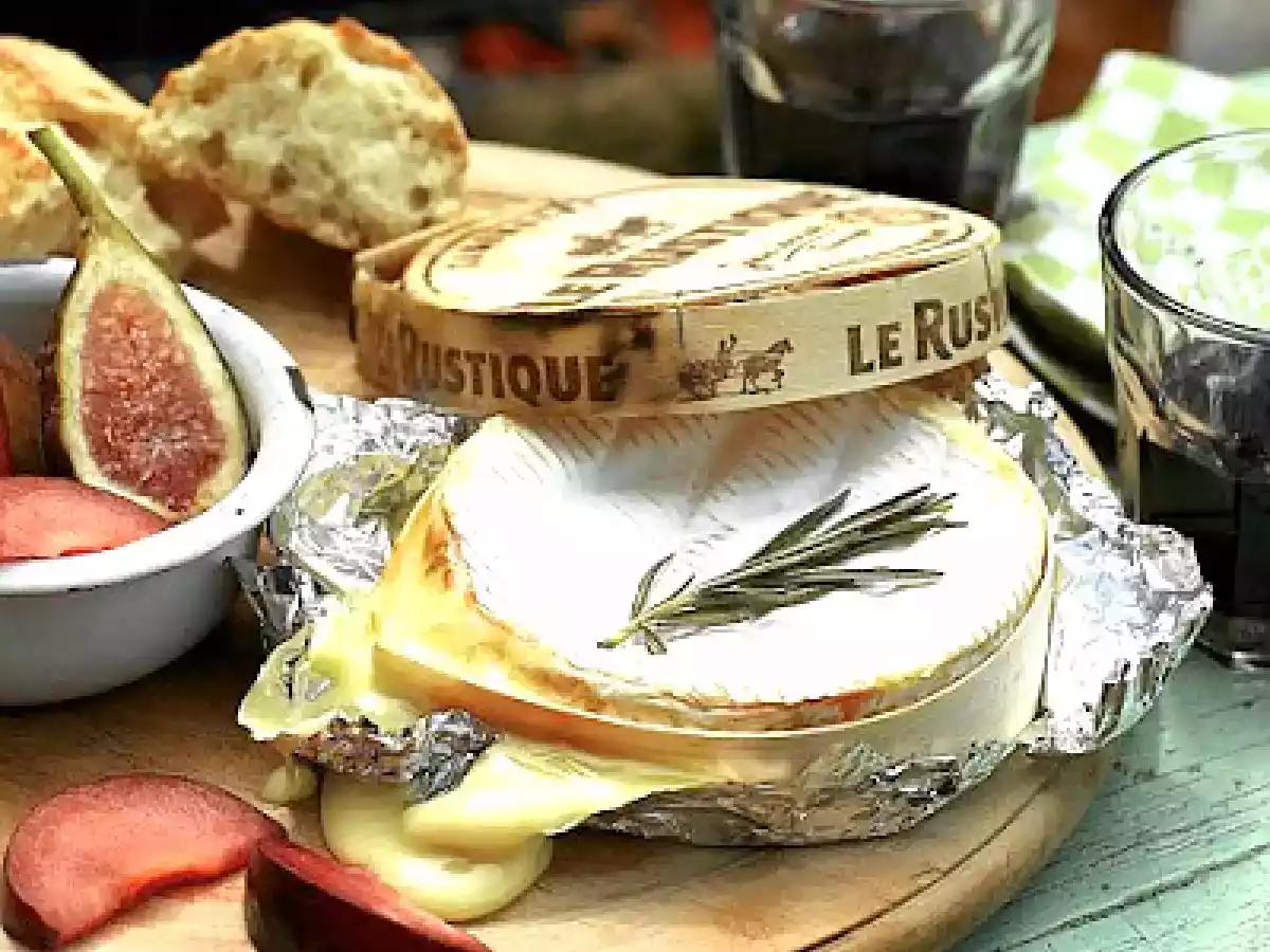 Camembert en su caja de madera con higos frescos y ciruelas