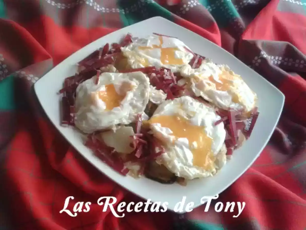 Huevos rotos con patatas a lo pobre y virutas de jamon Serrano